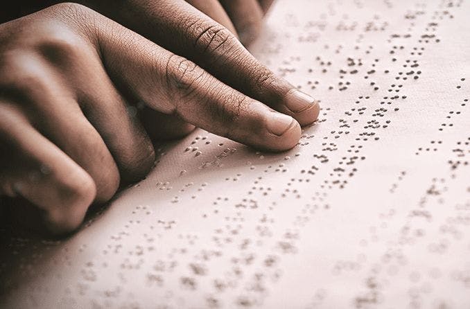 person reading braille with their fingers